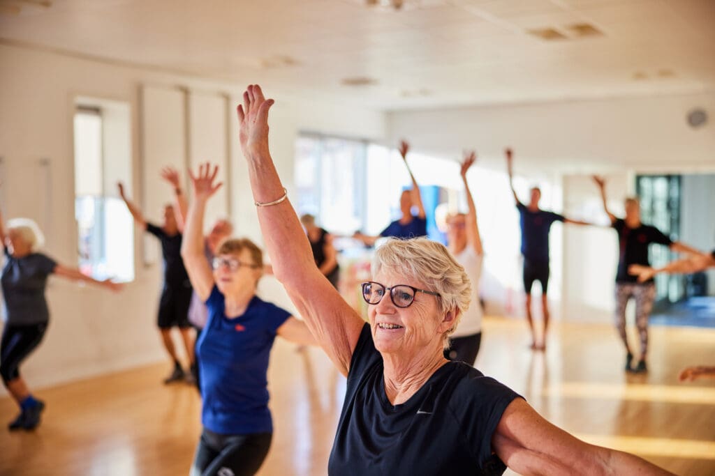 Smiling senior woman and others taking a group exercise class