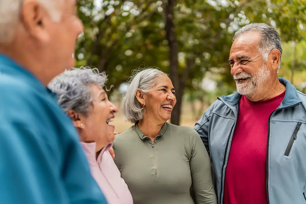 What Happens When Wellness for Seniors Becomes Part of Everyday Life 2 A group of cheerful Village at Proprietors Green residents smile and laugh together outdoors in athletic attire, highlighting social connection as a key part of wellness for seniors.