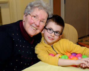 Adeline Murphy, a resident at Village at Proprietors Green, shares a smile with James Boland as he displays his cache of eggs.
