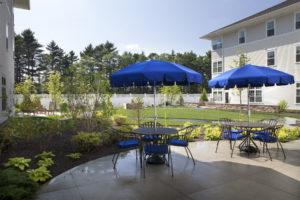 Outdoor patio tables with blue umbrellas at Village at Proprietors Green