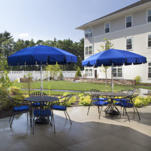 Outdoor patio tables with blue umbrellas at Village at Proprietors Green